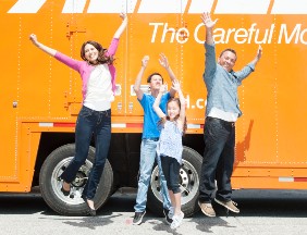 A family celebrating in front of a moving truck
