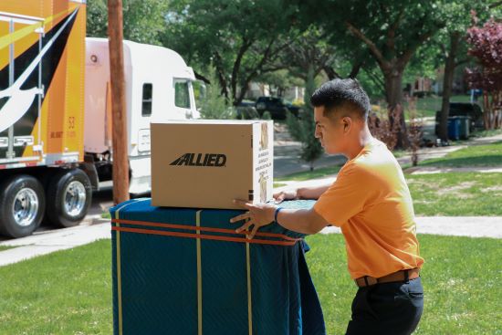 Allied Van Lines employee with boxes in front of moving truck