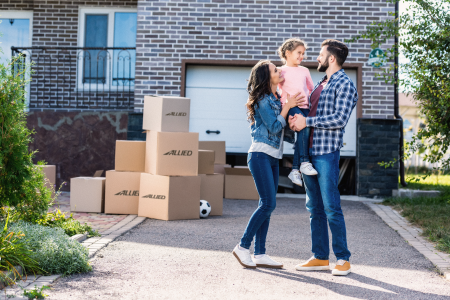 Family of three standing near Allied Van Lines moving boxes