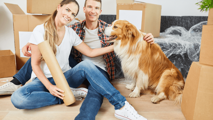 Couple with dog sitting near moving boxes