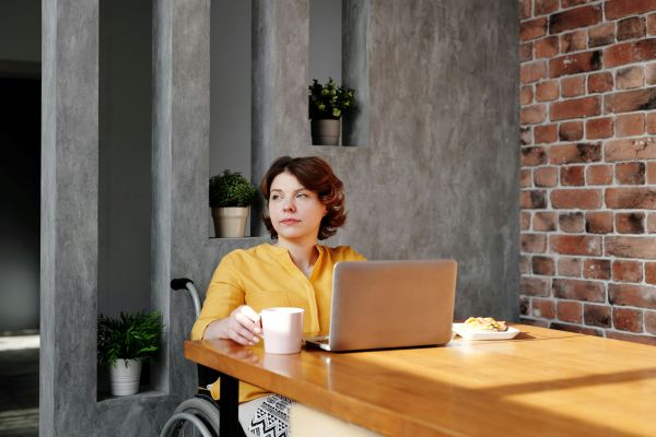 A woman in a wheelchair working on a laptop at home