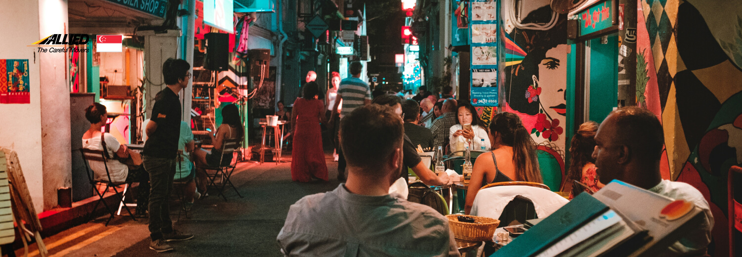 people sitting on chair near street during night time - arab street singapore