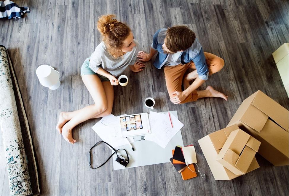 Couple sitting on ground with coffees and moving boxes