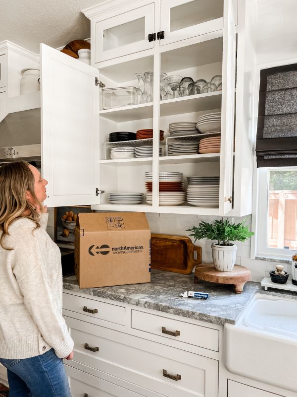 Woman looking at kitchen cabinets with North American moving box
