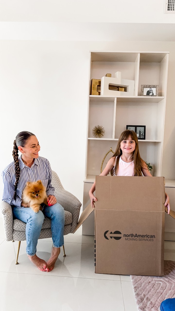 Mother smiling at her daughter in a North American Moving Services moving box