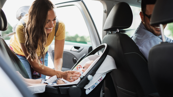 Mom putting baby in car seat