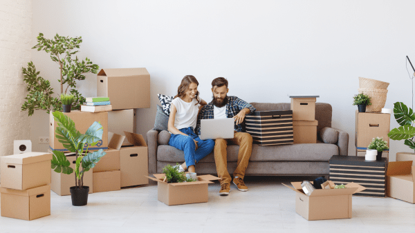 Couple sitting on a couch in a room full of moving boxes