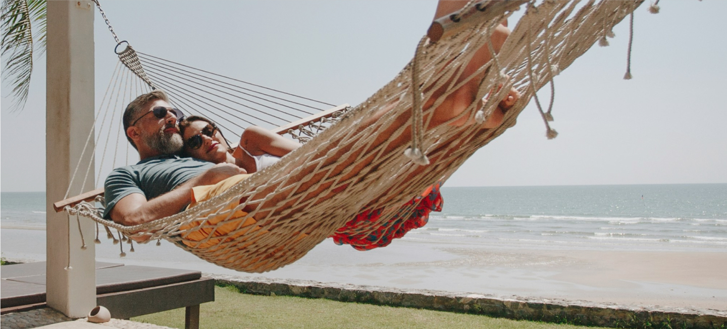 couple lounging in a hammock on the beach